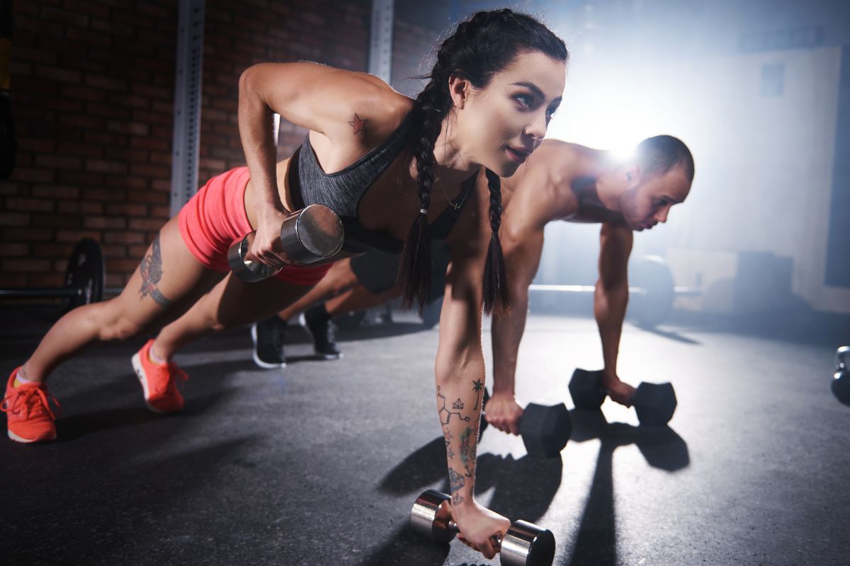 a couple can be seen exercising with weights together at a gym