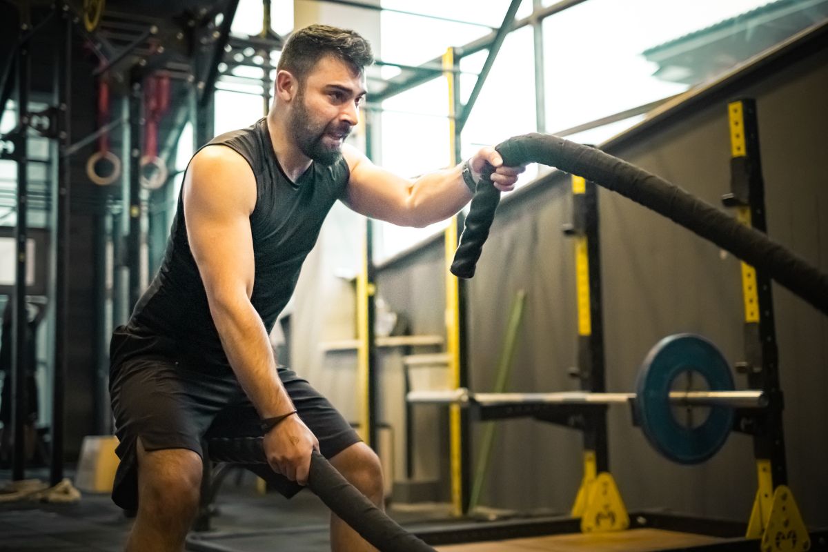 a man exercises using battle ropes at a gym