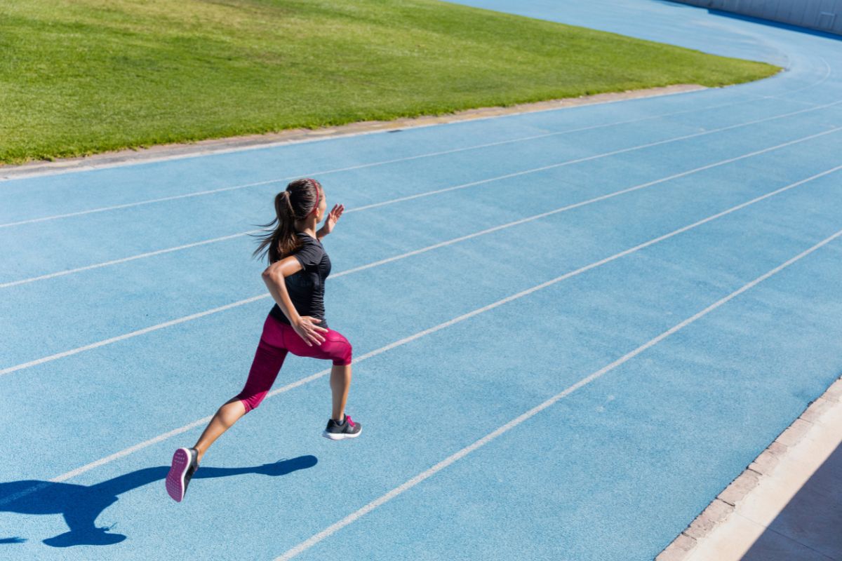 woman sprints on a blue track