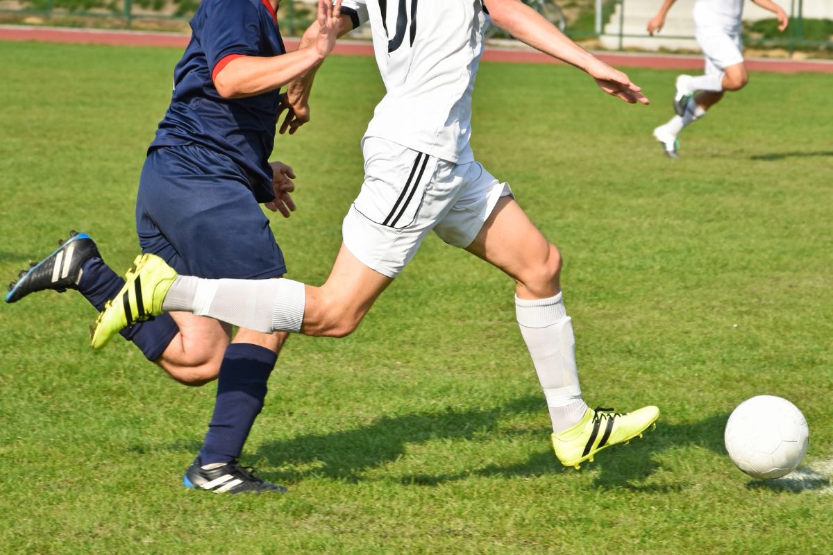 two soccer players can be seen competing for the ball during a match
